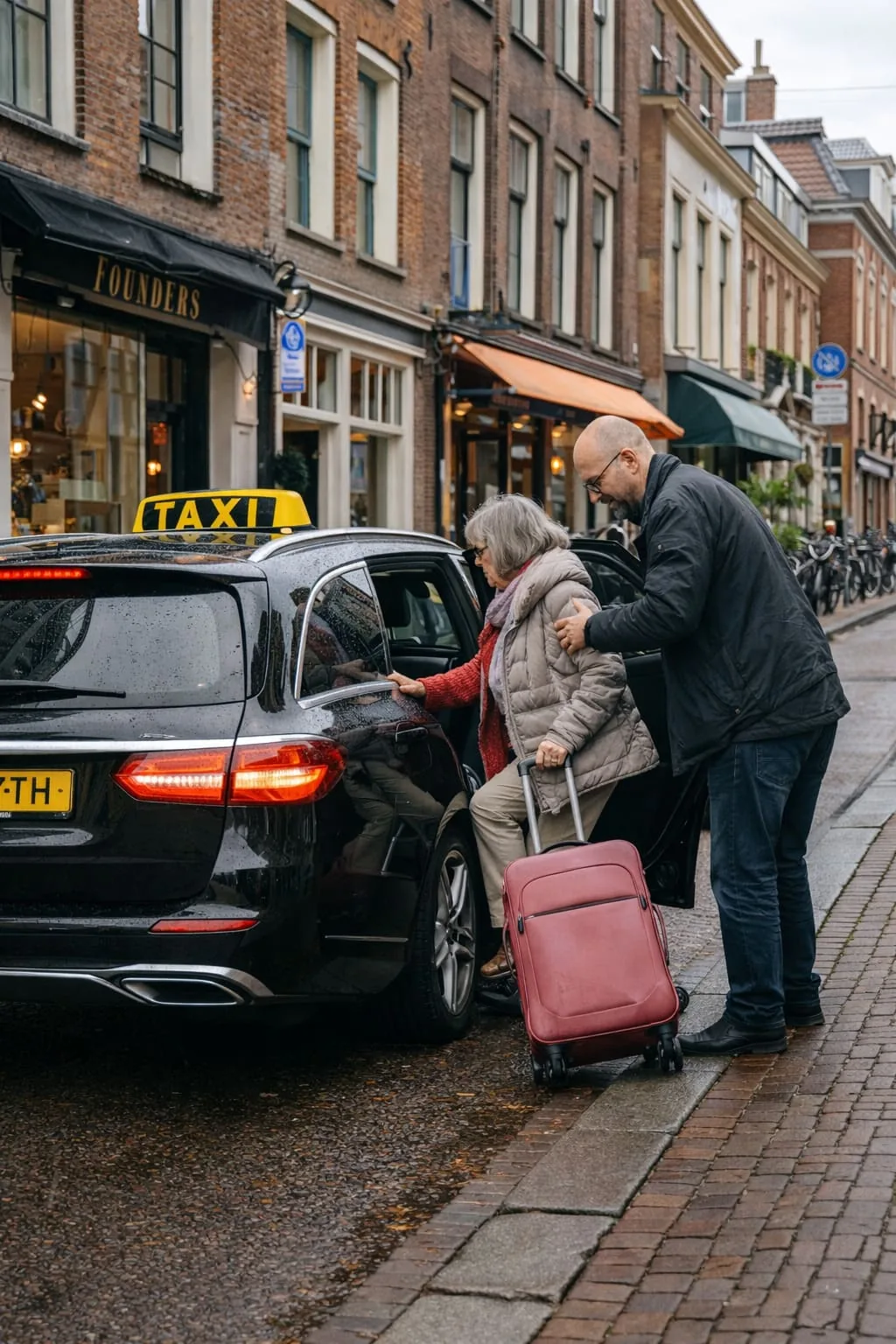 Professionele taxichauffeur helpt passagier instappen in zwarte Mercedes taxi in Haarlem
